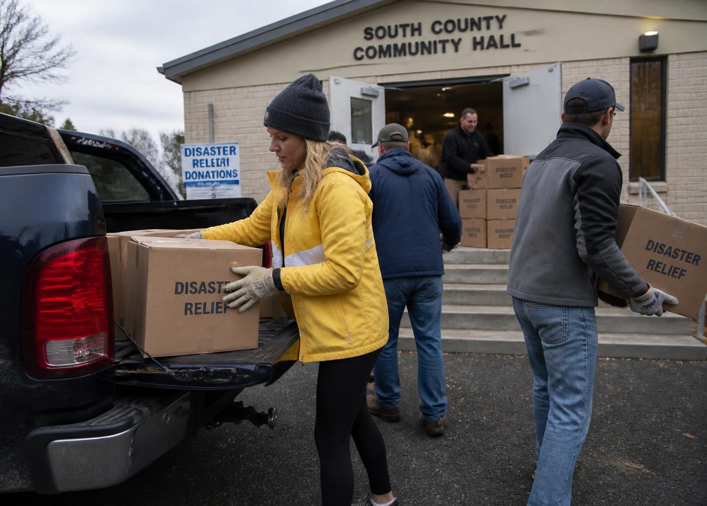 Volunteers loading disaster relief supplies outside a community hall